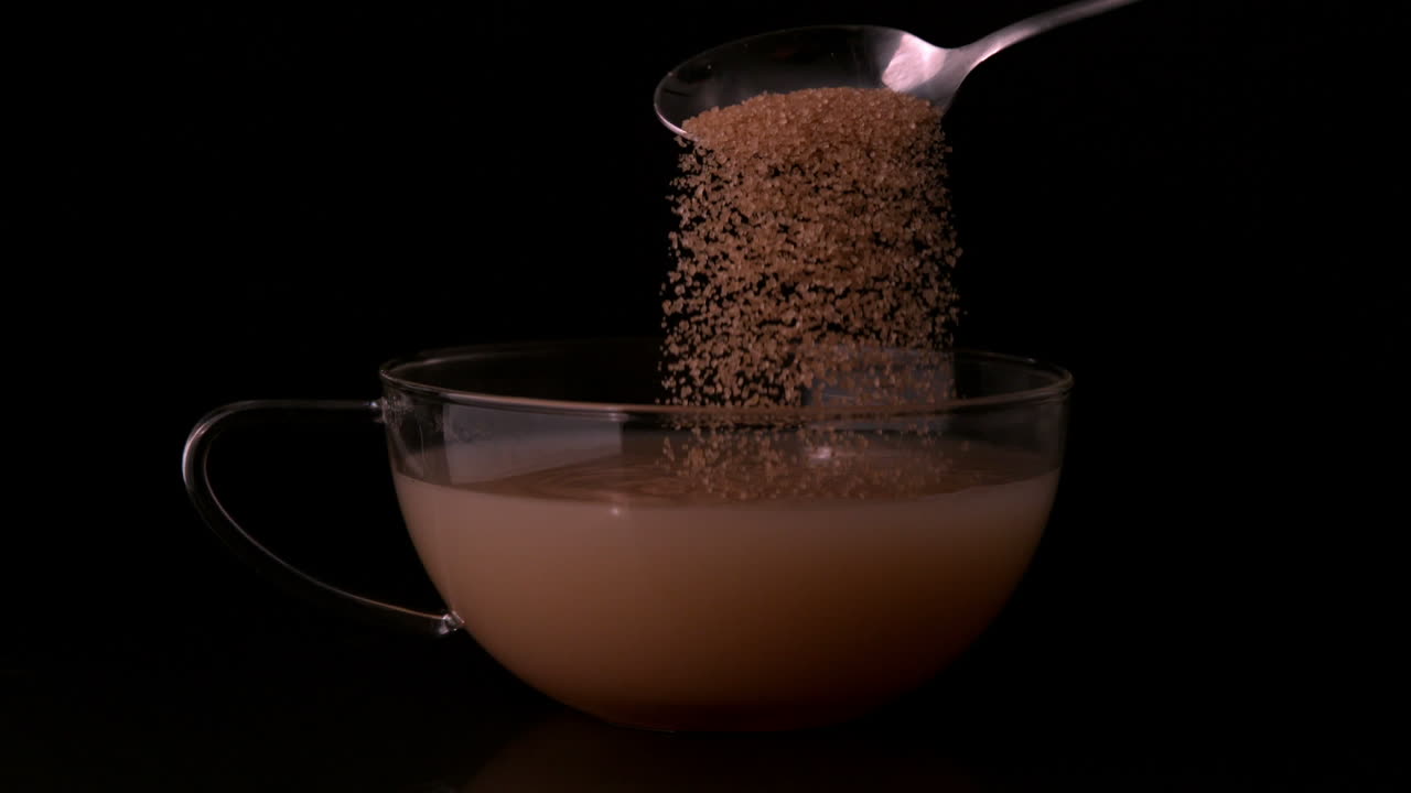 Cucchiaino che versa zucchero in una tazza di tè