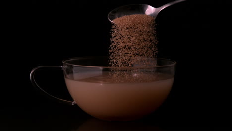 teaspoon pouring sugar into cup of tea