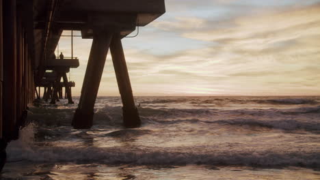 sunset under the pier with ocean waves