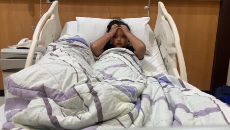 asian little girl lying on the bed on hospital while suffering from headache and cough