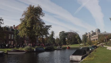 Menschen-Säumen-Die-Straßen-Eines-Kanals-In-Leiden,-Niederlande,-Anlässlich-Der-Jährlichen-Feier-Zur-Befreiung-Von-Leiden-Am-3.-Oktober,-Mit-Dem-Leidener-Observatorium-Im-Hintergrund