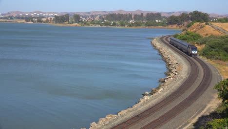 an amtrak train passes along a shoreline in the bay area of california