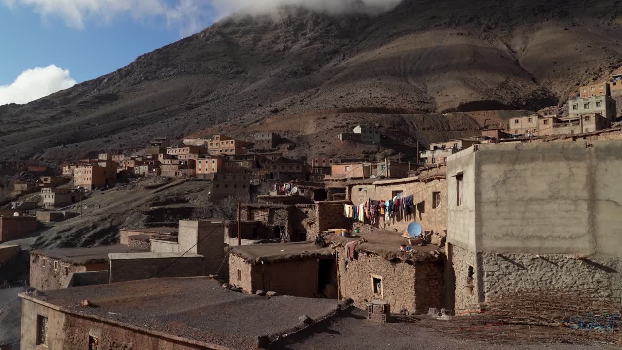 Inside the mountain village, winding paths lead to hidden courtyards where local life thrives, while the snow-covered peaks of Toubkal rise majestically beyond the village in Morocco