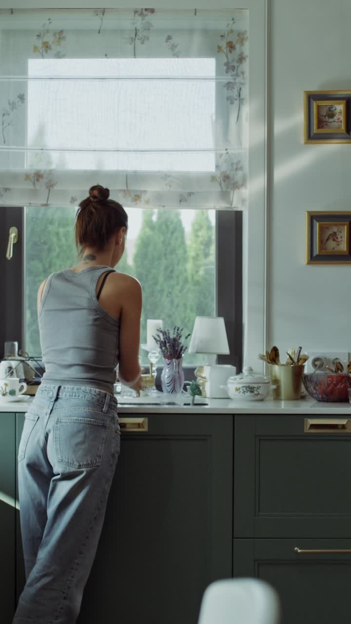 Donna che beve acqua in cucina