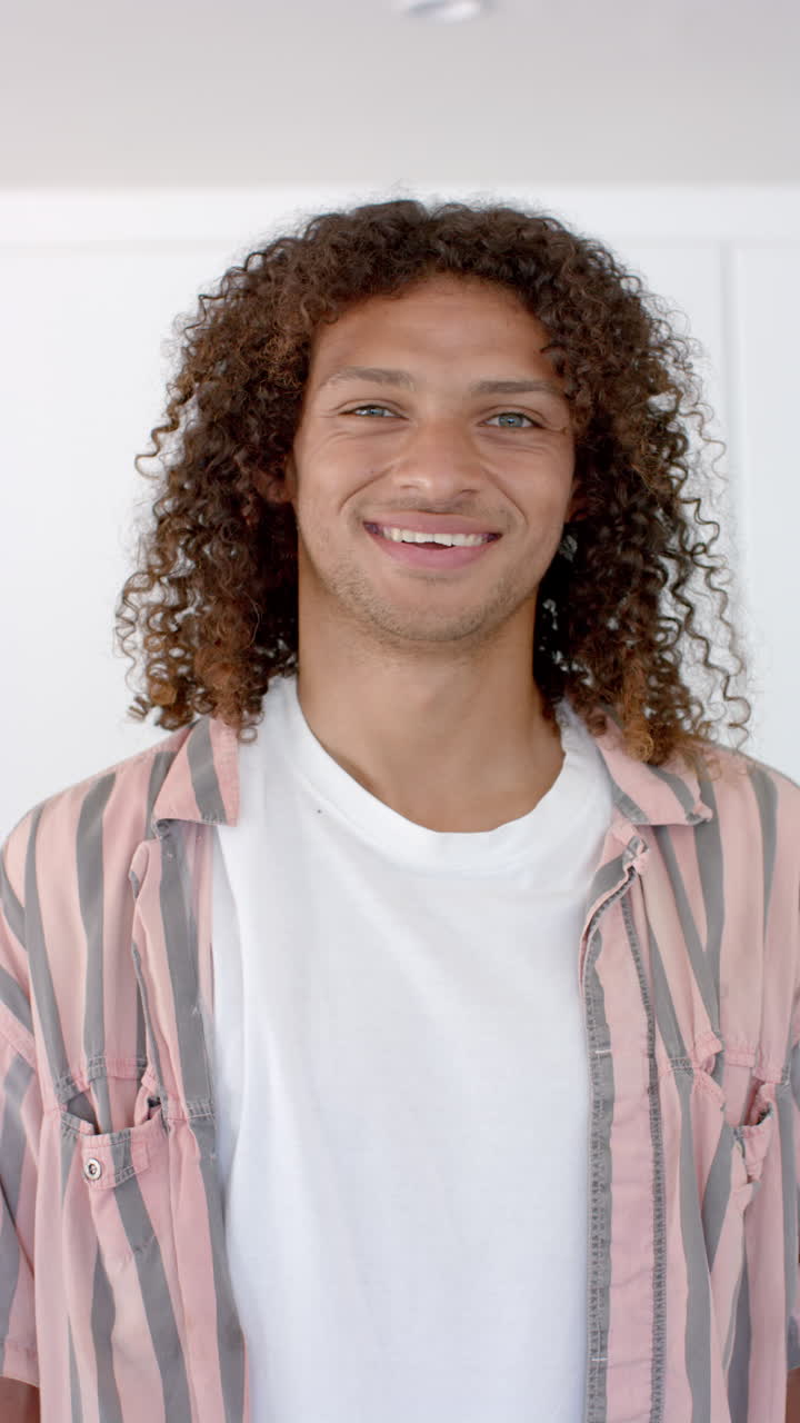 Vertical video: A young man with a cheerful smile stands confidently