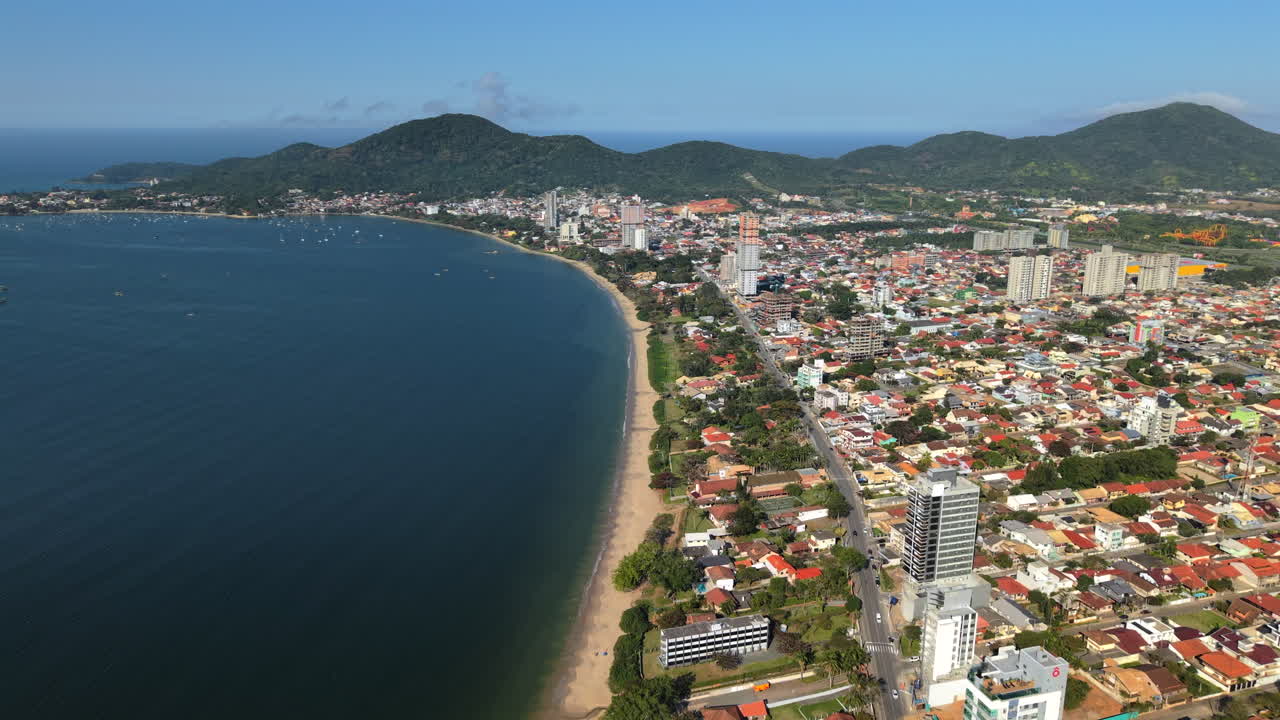 Una splendida vista aerea panoramica di Penha, Brasile. Il drone cattura l'intera baia, la lunga spiaggia sabbiosa, la città costiera e le bellissime montagne verdi sullo sfondo.