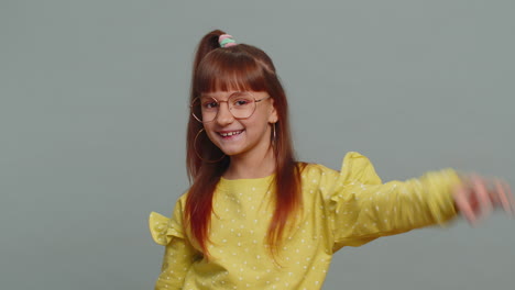 young toddler school girl in glasses looking approvingly at camera showing okey gesture like sign