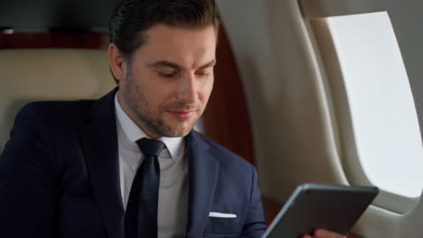 successful manager tapping tablet in plane closeup. focused ceo using computer