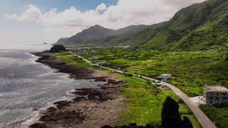 aerial drone flight over coastal road on green growing orchid island with sunlight and shadows in taiwan