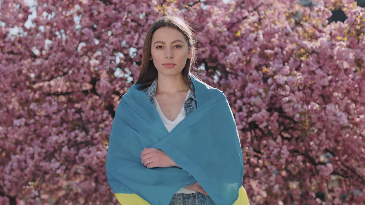 Donna con la bandiera ucraina tra i ciliegi in fiore