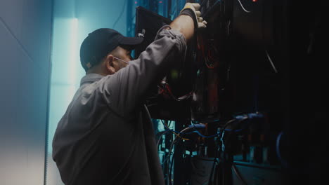 technician working on server rack in data center at night