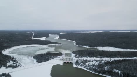 extreme high altitude drone out long snow covered road with rushing water notigi hydroelectric dam in the arctic