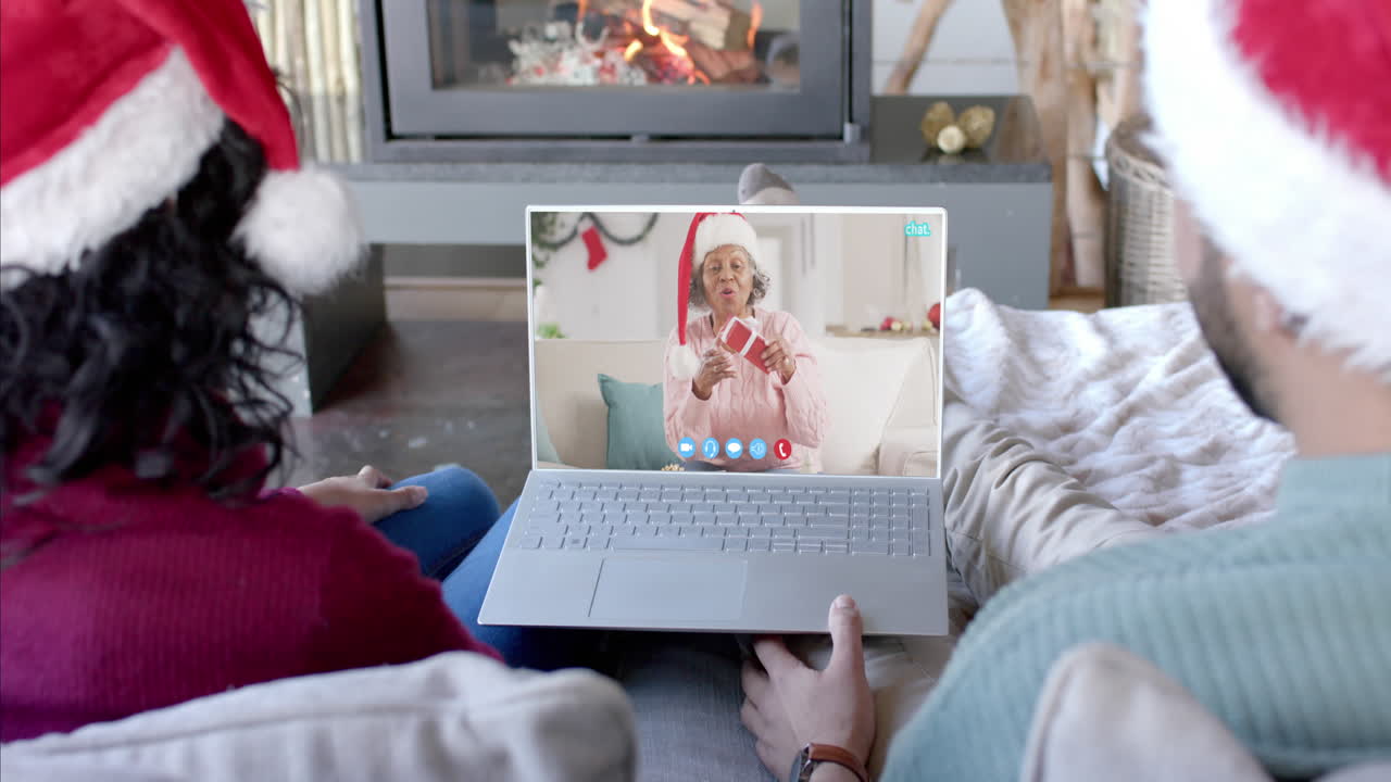 Coppia felice e madre anziana che fanno una videochiamata di Natale tramite laptop, al rallentatore.