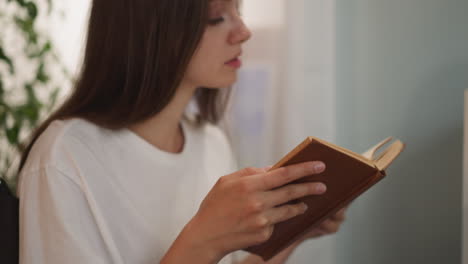 focused woman with paralysis reads red book flipping pages