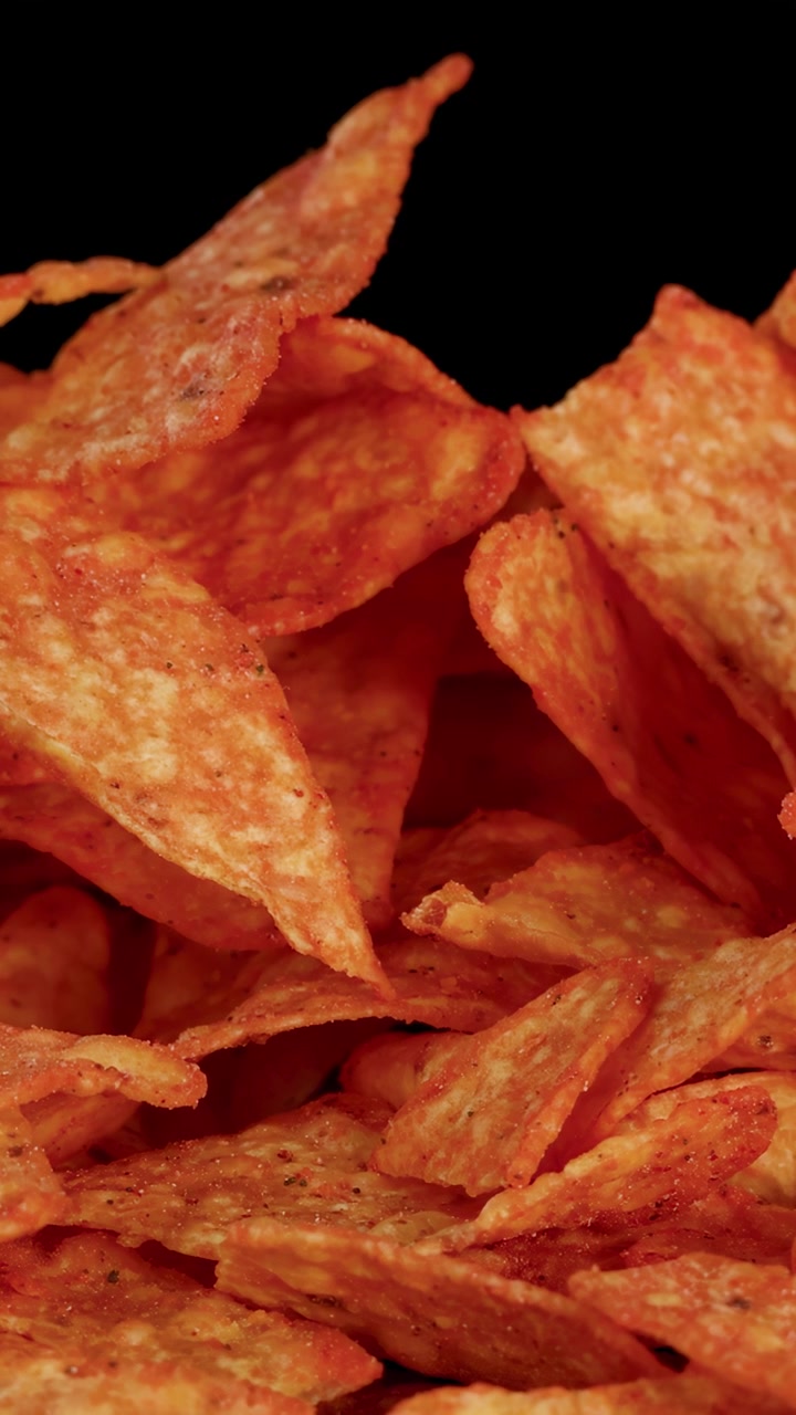 Un movimento di telecamera ravvicinato rivela croccanti tortilla chips condite sotto un'illuminazione drammatica da studio