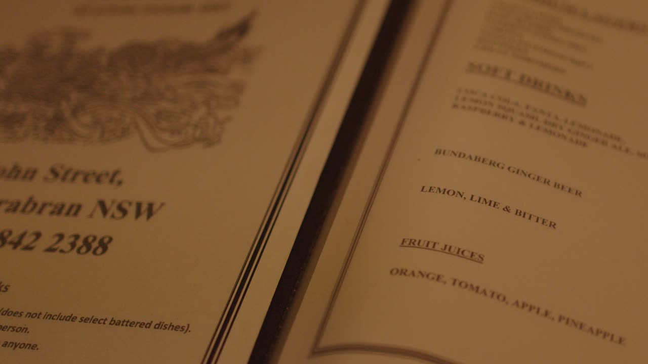 Close-up of hand flipping wine menu pages under warm ambient lighting in upscale restaurant setting