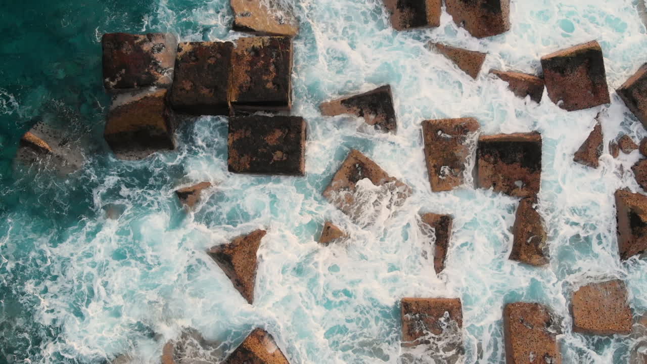 Top view Steep volcanic shore, reefs of frozen volcanic lava, stormy ocean, white foam from the giant waves that hit rocks. Aerial shot. Garachico, Tenerife, Canary Islands.