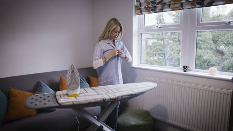 woman ironing shirt in living room