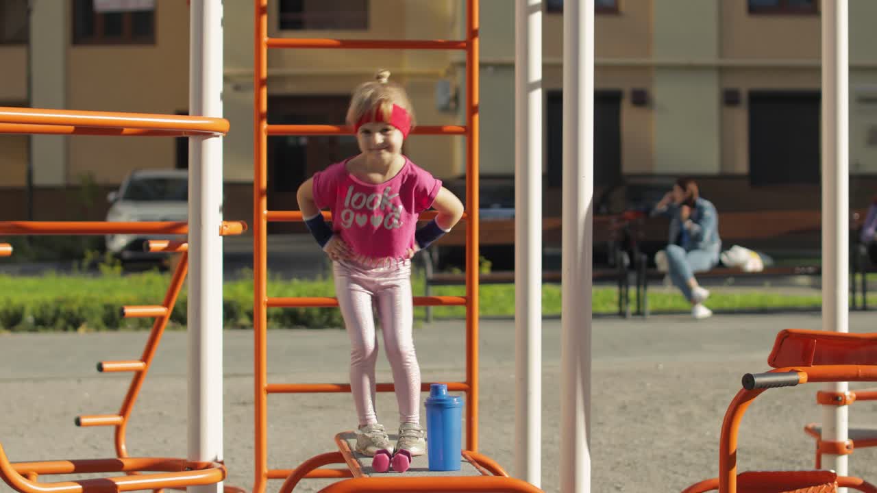niña linda en ropa deportiva haciendo ejercicios de gimnasta de fitness en el patio de recreo. entrenamiento para niños