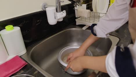 person washing rice grains in a pot in the kitchen sink