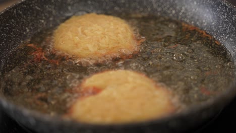 close-up de freír hojaldres de patata hashbrown caseros frescos en aceite