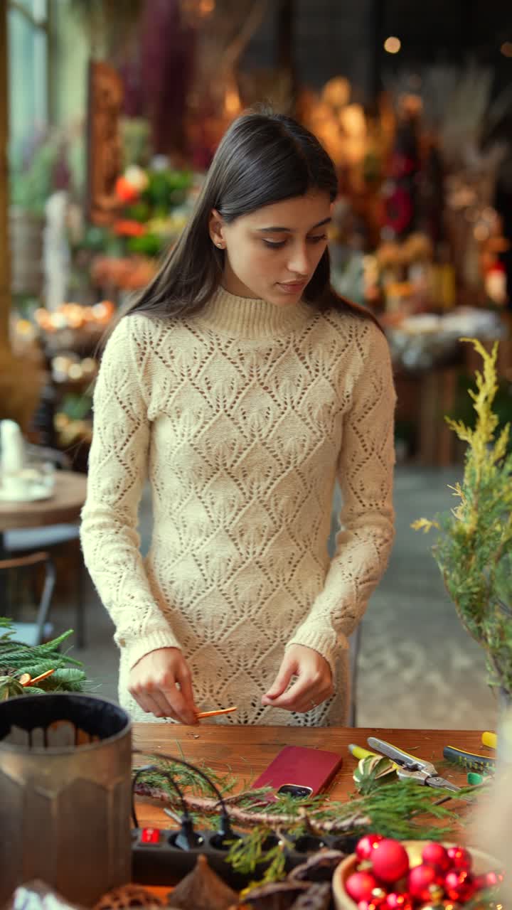 mujer creando una decoración navideña en una tienda de flores