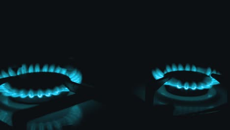 turn three on gas burners, blazing with blue flame, at night in kitchen. close