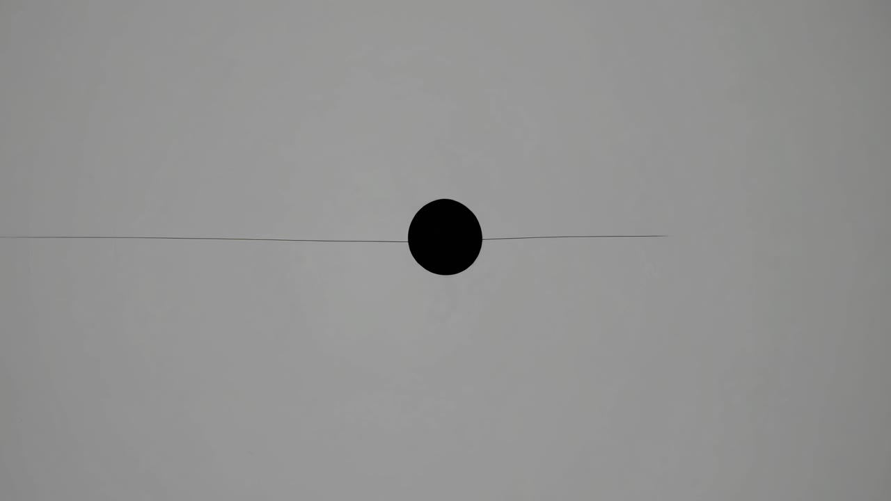 Minimalist video concept with a centered black dot on a gray background
