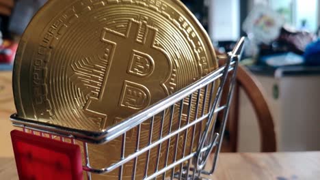 monedas criptográficas bitcoin doradas en un pequeño carrito de compras en la mesa de la cocina concepto cerrar órbita derecha