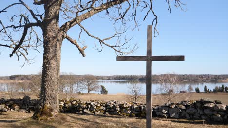 wide shot of christian catholic cross in field during day with water pond in the background