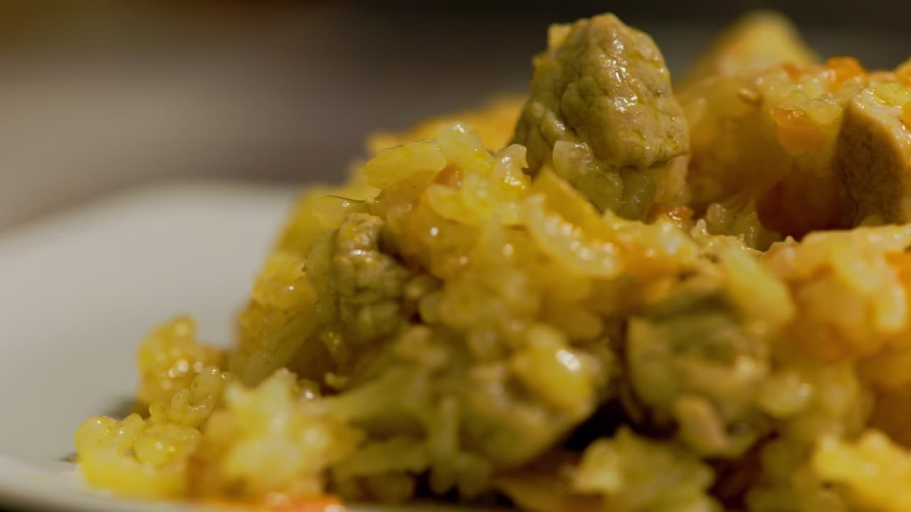 plato de pilaf caliente, pilau, pilaw o pilaf con carne de pavo girando en el plato