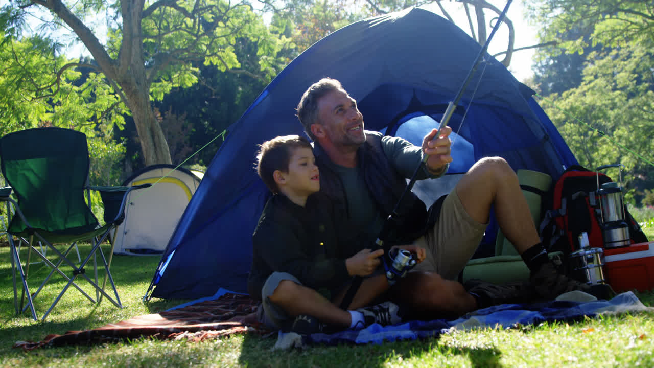 padre e hijo sosteniendo una caña de pescar fuera de la tienda