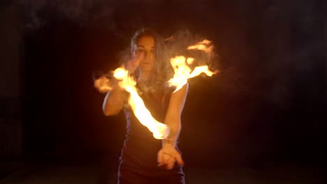 una artista de yong hace un espectáculo de fuego en la oscuridad a cámara lenta.