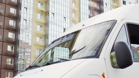 tracking shot of man in blue uniform driving mail delivery van in city