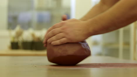 pottery craftsman hands rolling raw clay material preparing creation on workshop surface