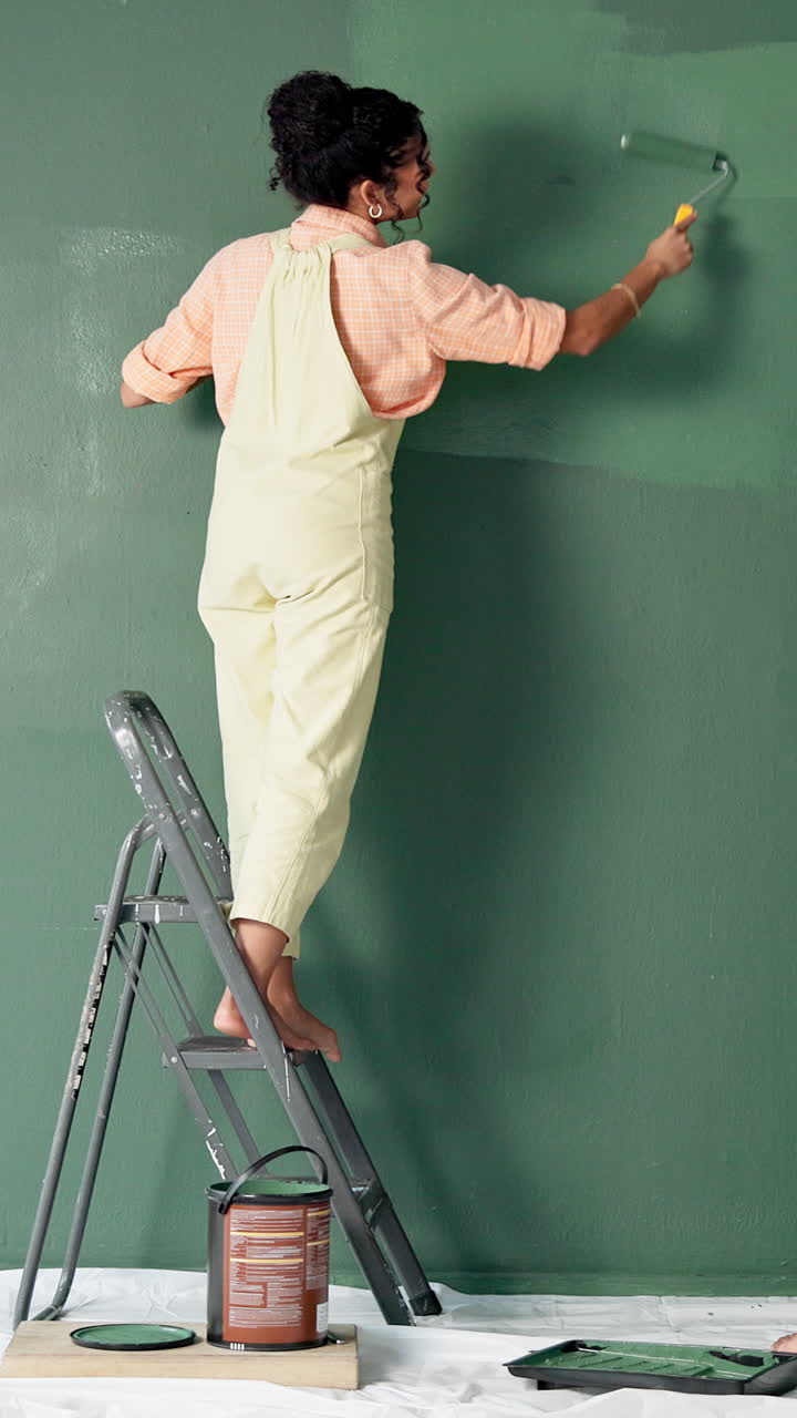 Woman painting a green wall at home