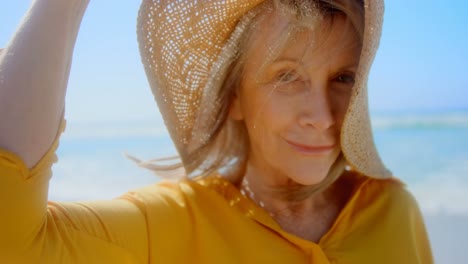 front view of active senior caucasian woman in hat standing on the beach 4k