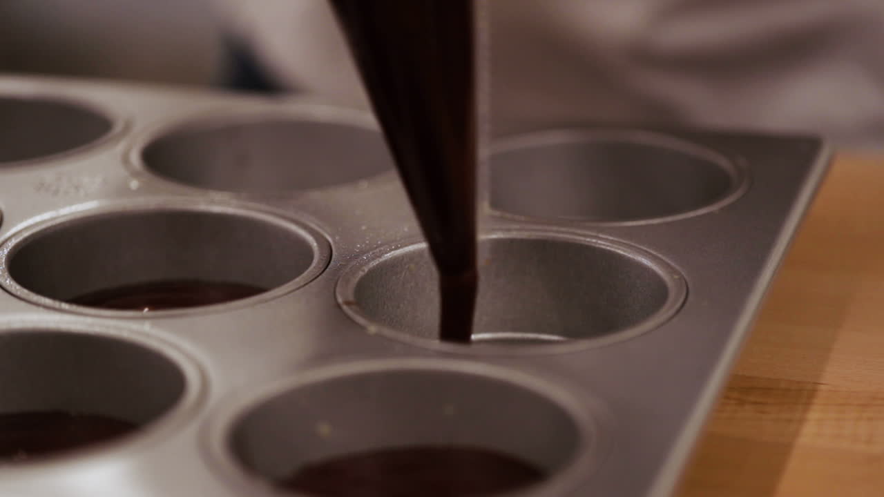 шеф-повар наполняет лоток для кексов смесью для брауни