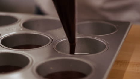 chef llenando bandeja de cupcakes con mezcla de brownie