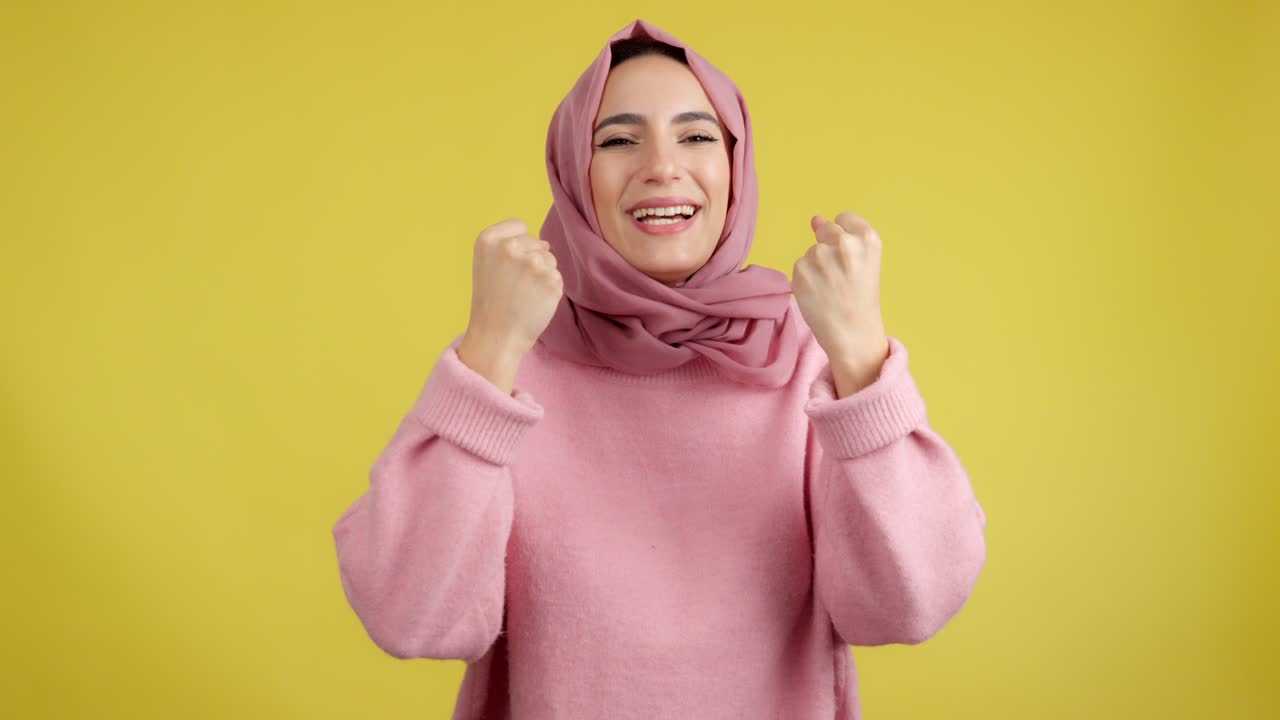 Happy Muslim Woman Celebrating or Expressing Joy on Yellow Background