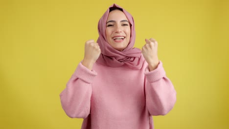 happy muslim woman celebrating or expressing joy on yellow background
