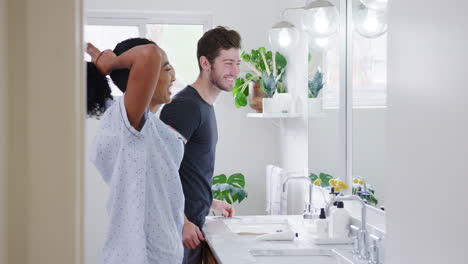 couple wearing pyjamas standing in bathroom looking in mirror in the morning