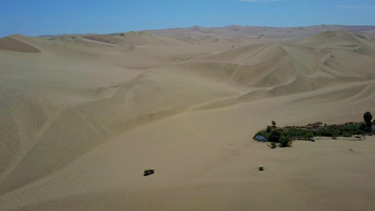 공중 드론 촬영에서 페루의 오아시스를 향해 모래 언덕을 따라 운전하는 후아치나 버기