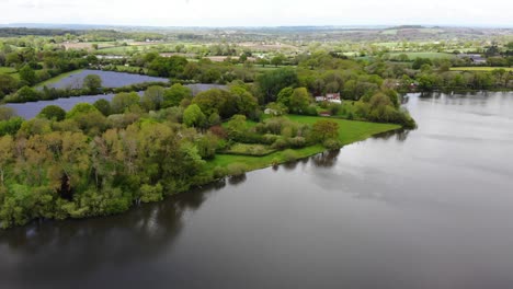 aerial panning right shot of chard reservoir south west england with a solar farm in the background on a sunny day