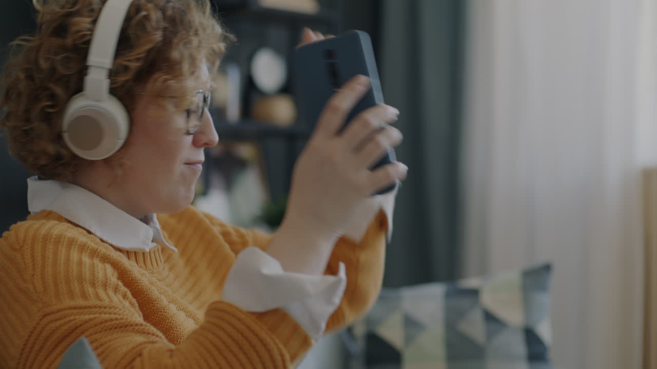 mujer relajándose en casa con auriculares y teléfono