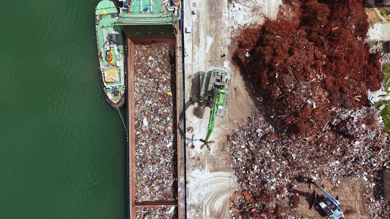 Nave da carico scarica materiale di scarto in un sito di smaltimento vicino all'acqua a metà giornata in una giornata di sole.