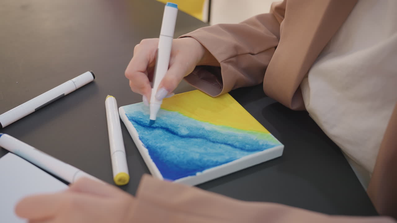 신중한 손길로 작은 바다 풍경을 완성하고, 아티스트는 정교한 터치를 사용하여 미니어처 바다 그림을 마무리합니다. 집중된 손은 마커를 사용하여 작은 해안가 작품에 꼼꼼하게 하이라이트를 더합니다.