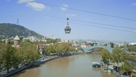 vista aérea de tbilisi en un funicular sobre el río mt&#39;k&#39;vari, vista de otoño, coches pasando, casco antiguo, puente de cristal