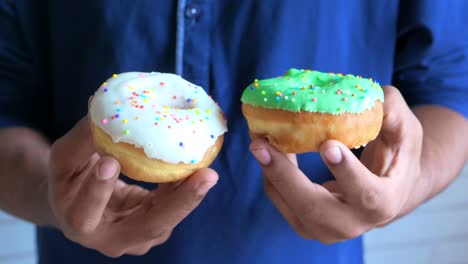 person holding two glazed donuts