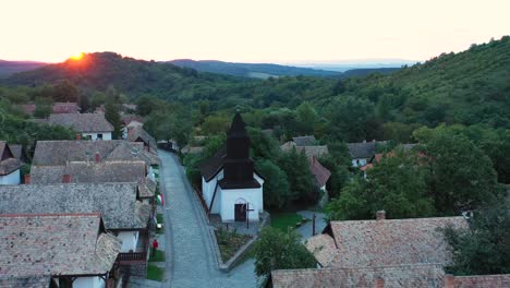 Drone-flies-over-the-historical-streets-of-Holloko,-Hungary-in-the-sunset